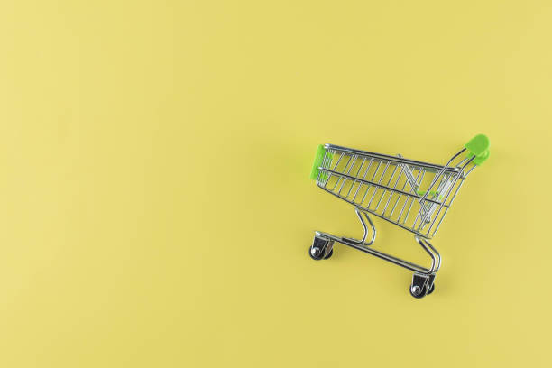 istock empty green small shopping cart on yellow background. Copy space, free place for text. 1346530449