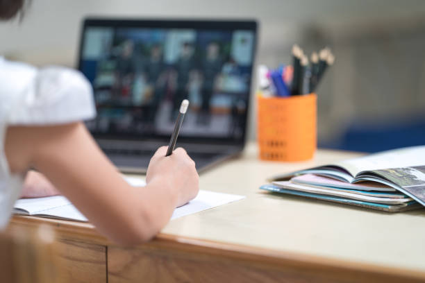 istock Asian children girl student writing on notebook while studying online via laptop while at home. Education Concept Stock Photo 1346531459