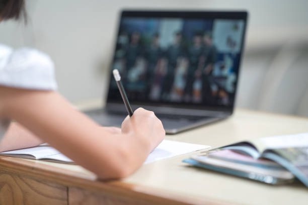 istock Asian children girl student writing on notebook while studying online via laptop while at home. Education Concept Stock Photo 1346531483