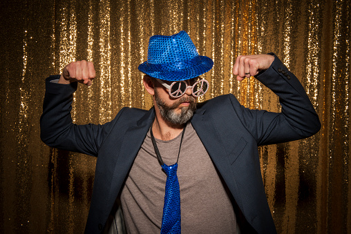 Portrait of mature man wearing comedy glasses and flexing muscles while enjoying party with props.