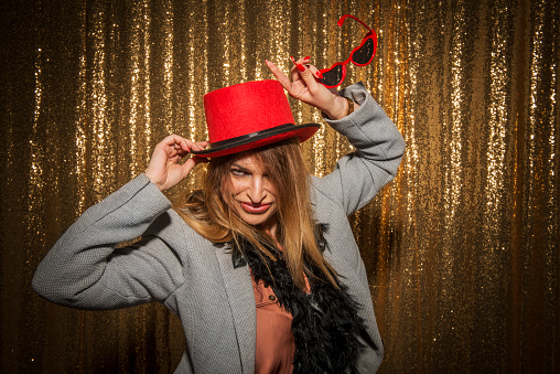 Portrait of happy mid adult woman wearing feather boa and top hat while enjoying the party.
