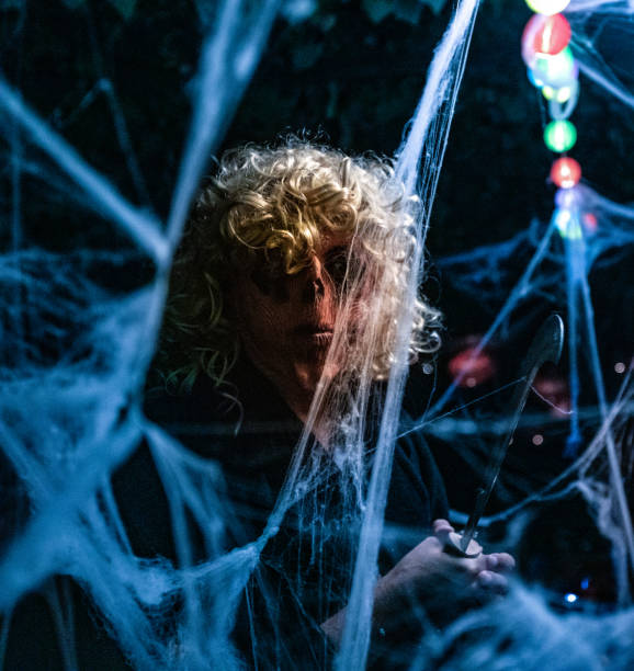 istock Spooky Man in Disguise Holding a Machete Amongst Spider Webs 1346535083