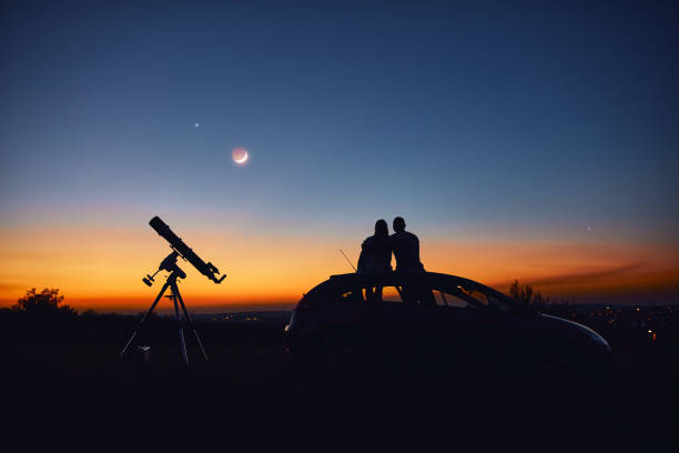 istock Couple stargazing together with a astronomical telescope. 1346536158