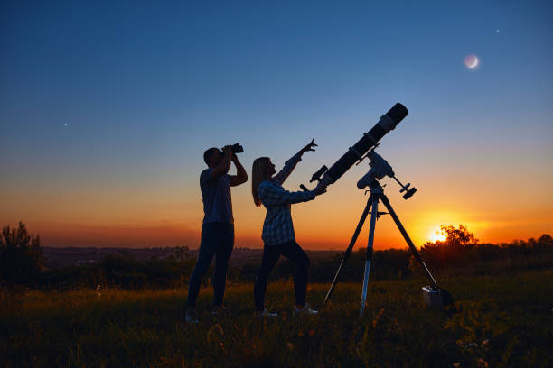 istock Couple stargazing together with a astronomical telescope. 1346536205