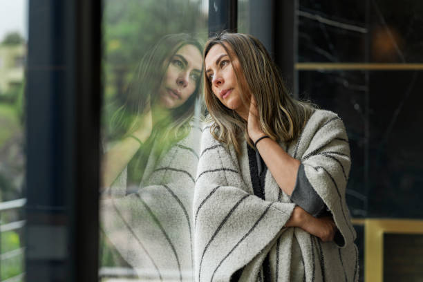 非常に退屈で悲しい女性は、孤立の多くの時間を探して彼女の家の窓に寄りかかっています - alcoholism assistance photography people ストックフォトと画像