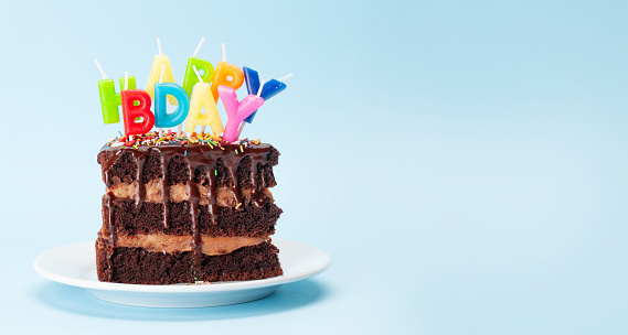 Birthday cake with happy birthday candles on blue background with copy space for your greetings