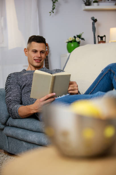 istock Young man lounging on the sofa and reading a book 1346537903