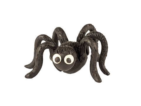 Funny black spider made of plasticine, isolated on a white background.