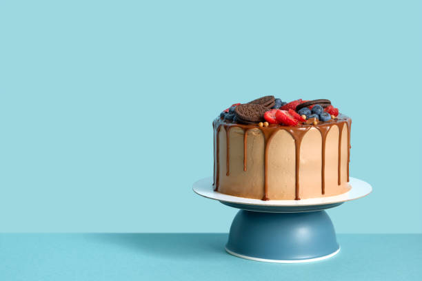 Chocolate birthday cake with berries and cookies on blue wall table background, copy space
