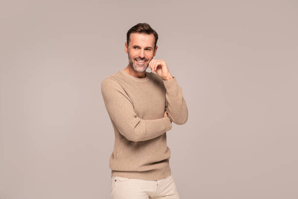 Cheerful handsome guy in fashionable autumn sweater posing in studio