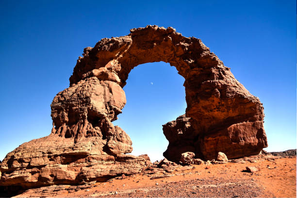 Arch Rock formation aka Arch of Africa or Arch of Algeria with moon at Tamezguida in Tassili nAjjer national park in Algeria stock photo