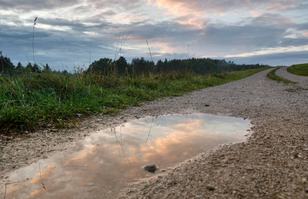 Reflections of a sunset sky in a rain puddle on a gravel road in rural landscape. Seen in Germany in October