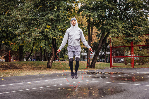 Young man with jumping rope on an autumn day training and prepares for the competition