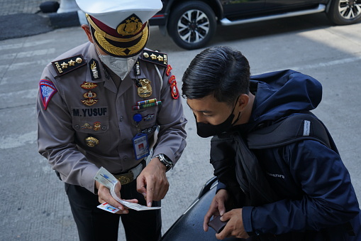 Makassar, Indonesia - October 13 2021: Indonesian police officers are checking the completeness of a motorist's vehicle. Police raid