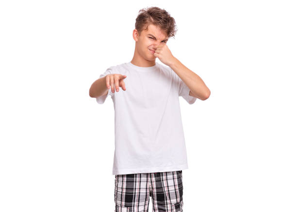 Handsome teen boy closes his nose from an unpleasant smell, isolated on white background