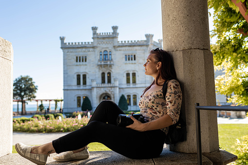 Adventurous female tourist taking a photo with her camera of the amazing architecture of Trieste