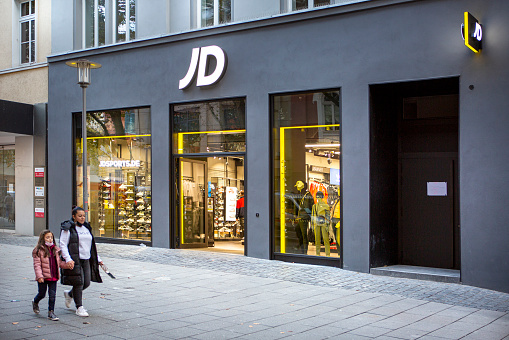 Wiesbaden, Germany - October 13, 2021: Entrance of JD store in the city center of Wiesbaden. JD Sports Fashion is a British sports-fashion retail company based in Bury, England. JD has shops throughout the United Kingdom, Europe, the United States, Asia, New Zealand and Australia. Some passersby in the foreground.