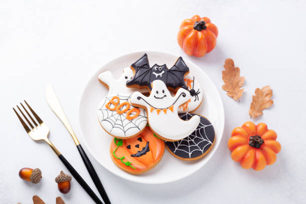 istock Halloween table setting with gingerbread cookies on white plate and cuterly on white background. Bright homemade cookies for Halloween party 1346551169