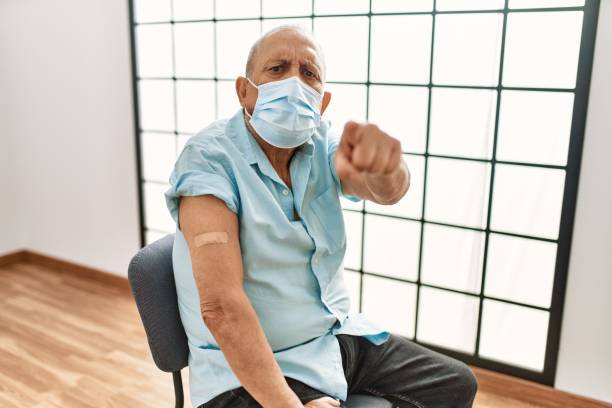 istock Mature hispanic man with grey hair getting vaccinated pointing with finger to the camera and to you, confident gesture looking serious 1346552432