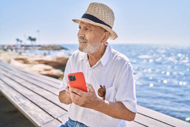 istock Senior man smiling confident wearing summer hat using smartphone at seaside 1346552470