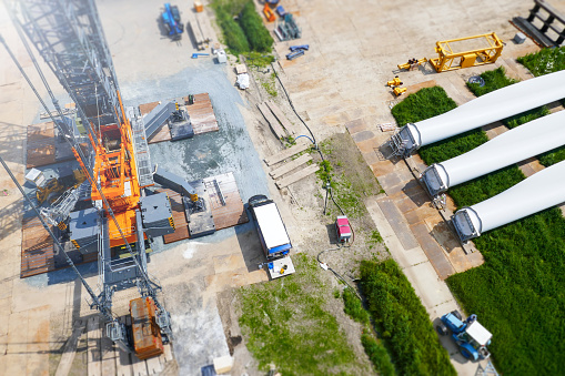 Wind farm construction - View from the top on tree 65m blades prepared to be installed on the wind turbine. Big industrial crane prepared to lift them up.