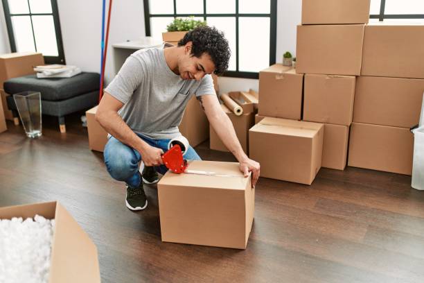 istock Young hispanic man smiling happy packing box at new home. 1346553941