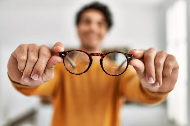 istock Young hispanic man smiling happy holding glasses at home. 1346554063