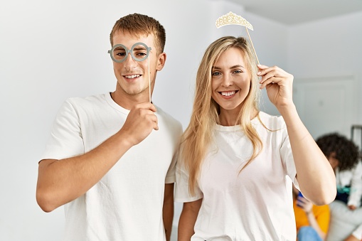 Two young friends having party using funny costume accessories at home.