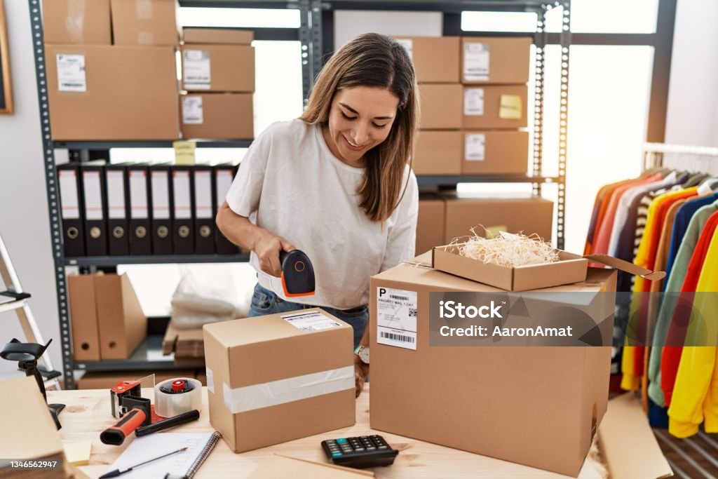 Young hispanic woman smiling confident working at store Entrepreneur Stock Photo