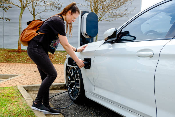 Woman near the electric refueling station carrying her car stock photo