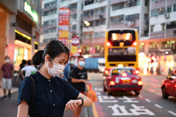 young woman wearing protective mask, checking time on smart watch. - china covid imagens e fotografias de stock