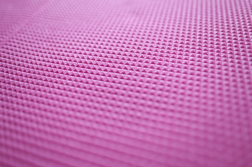 Closeup of pink rubber yoga mat background. Comfortable sports accessories concept