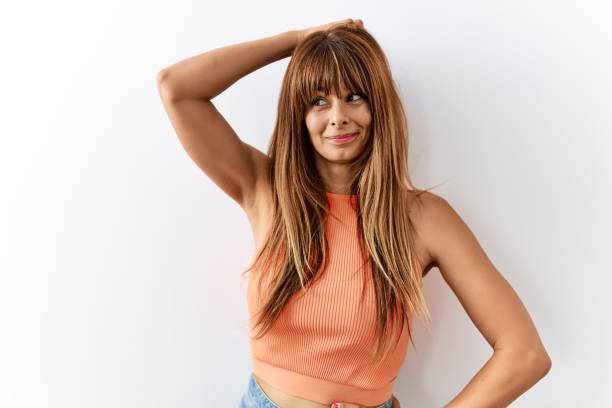 Hispanic woman with bang hairstyle standing over isolated background confuse and wondering about question. uncertain with doubt, thinking with hand on head. pensive concept. Hispanic woman with bang hairstyle standing over isolated background confuse and wondering about question. uncertain with doubt, thinking with hand on head. pensive concept. fringe stock pictures, royalty-free photos & images