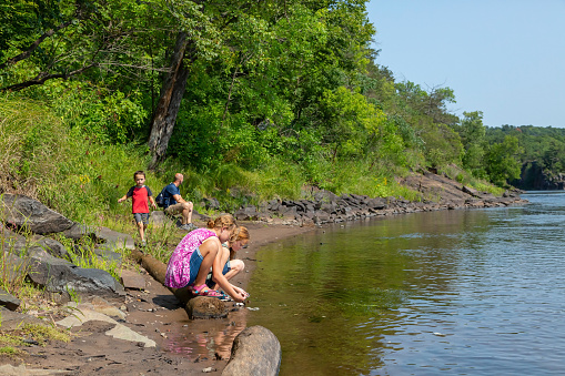 Father and three children on the bank of the St. Croix River on a beautiful summer day.