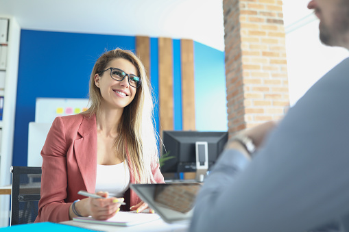 Business woman with glasses sitting at table and conducting interview with man. Employment concept