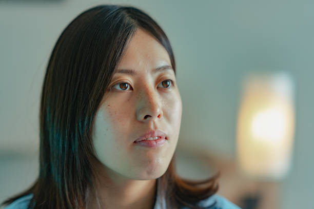 Young woman sitting on bed and looking at camera
