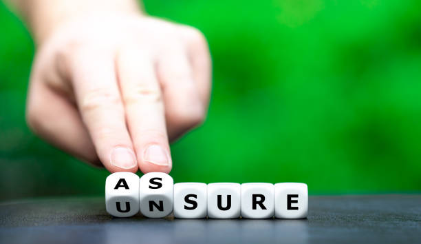 istock Hand turns dice and changes the word unsure to assure. 1346570299