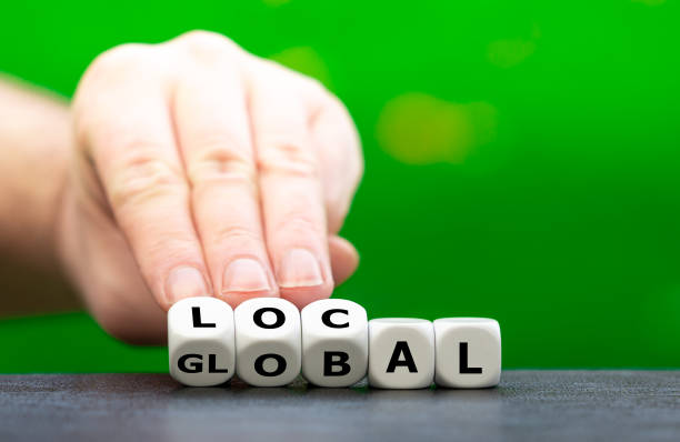 istock Hand turns dice and changes the word global to local. 1346570305