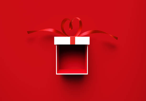 Open white gift box tied by heart shaped red ribbon on red background. Horizontal composition with copy space. Directly above. Great use for Christmas and Valentine's Day related gift concepts.