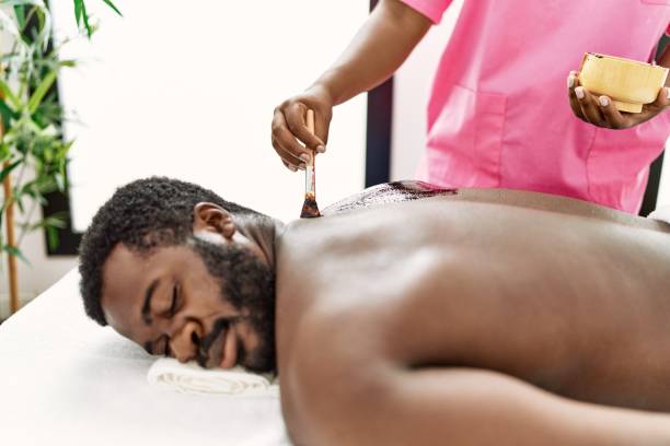 African american man reciving skin treatment on his back at beauty center. African american man reciving skin treatment on his back at beauty center. black male massage stock pictures, royalty-free photos & images