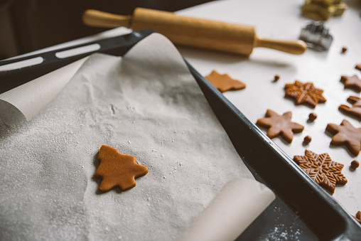 One small gingerbread cookie in the form of a Christmas tree on parchment Concept of preparation for Christmas and New Year, homemade desserts. Top view, minimalism