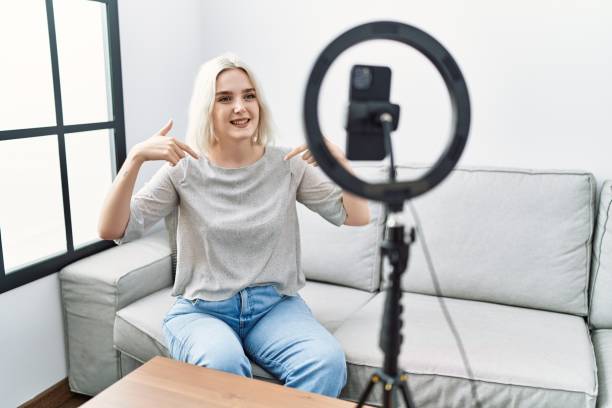 istock Young caucasian woman recording vlog tutorial with smartphone at home looking confident with smile on face, pointing oneself with fingers proud and happy. 1346573466