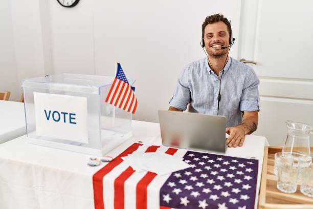 istock Handsome young man working at political campaign wearing operator head seat looking positive and happy standing and smiling with a confident smile showing teeth 1346574750