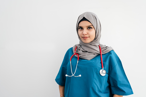 Confident female nurse. Confident Muslim female doctor standing with isolated gray. Closeup portrait of friendly, smiling confident Muslim female doctor. Portrait of Muslim nurse with stethoscope