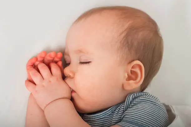 Healthy restful sleep for child up to one year old. Infant and sleep problems in bed. Baby sucking thumb