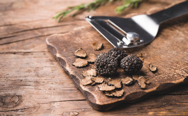 black truffles mushrooms and truffles knife on rustic wooden table, copy space for text, selective focus - truffle tuber melanosporum mushroom 個照片及圖片檔