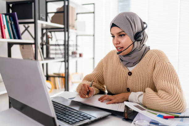 signora islamica nera in hijab e cuffia con videochiamata sul laptop - internet computer hands free device telephone foto e immagini stock