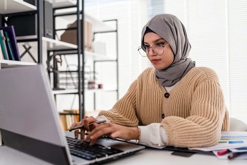 Muslim business woman  working in office. Happy arab woman working in company service center  using laptop. Islamic business woman working on computer  with copy space.