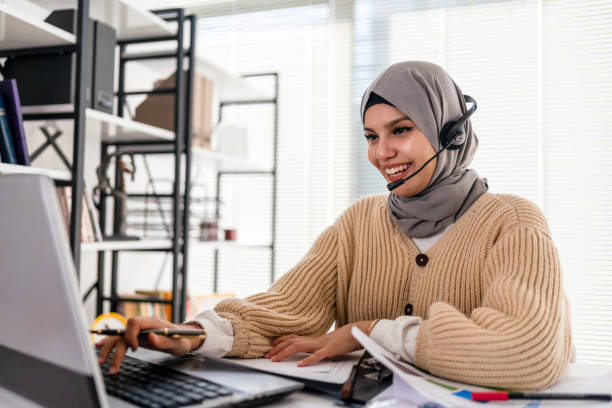 Black Islamic Lady In Hijab And Headset Having Video Call On Laptop stock photo