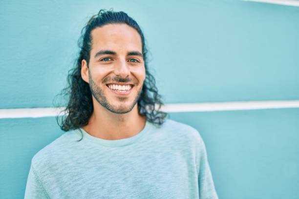 istock Young hispanic man smiling happy looking to the camera leaning on the wall 1346578101
